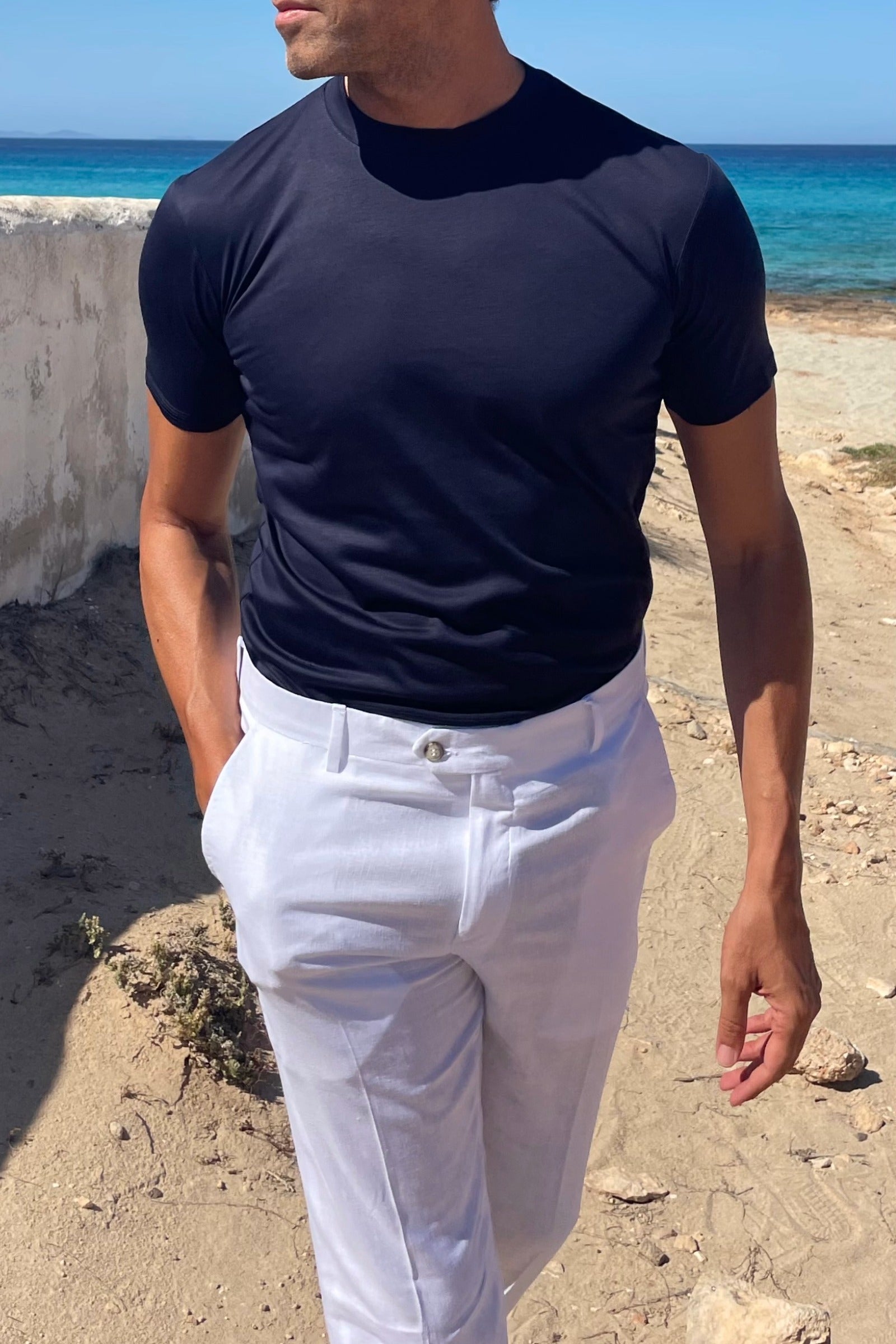 Camiseta azul marino de hombre con pantalón de lino blanco.