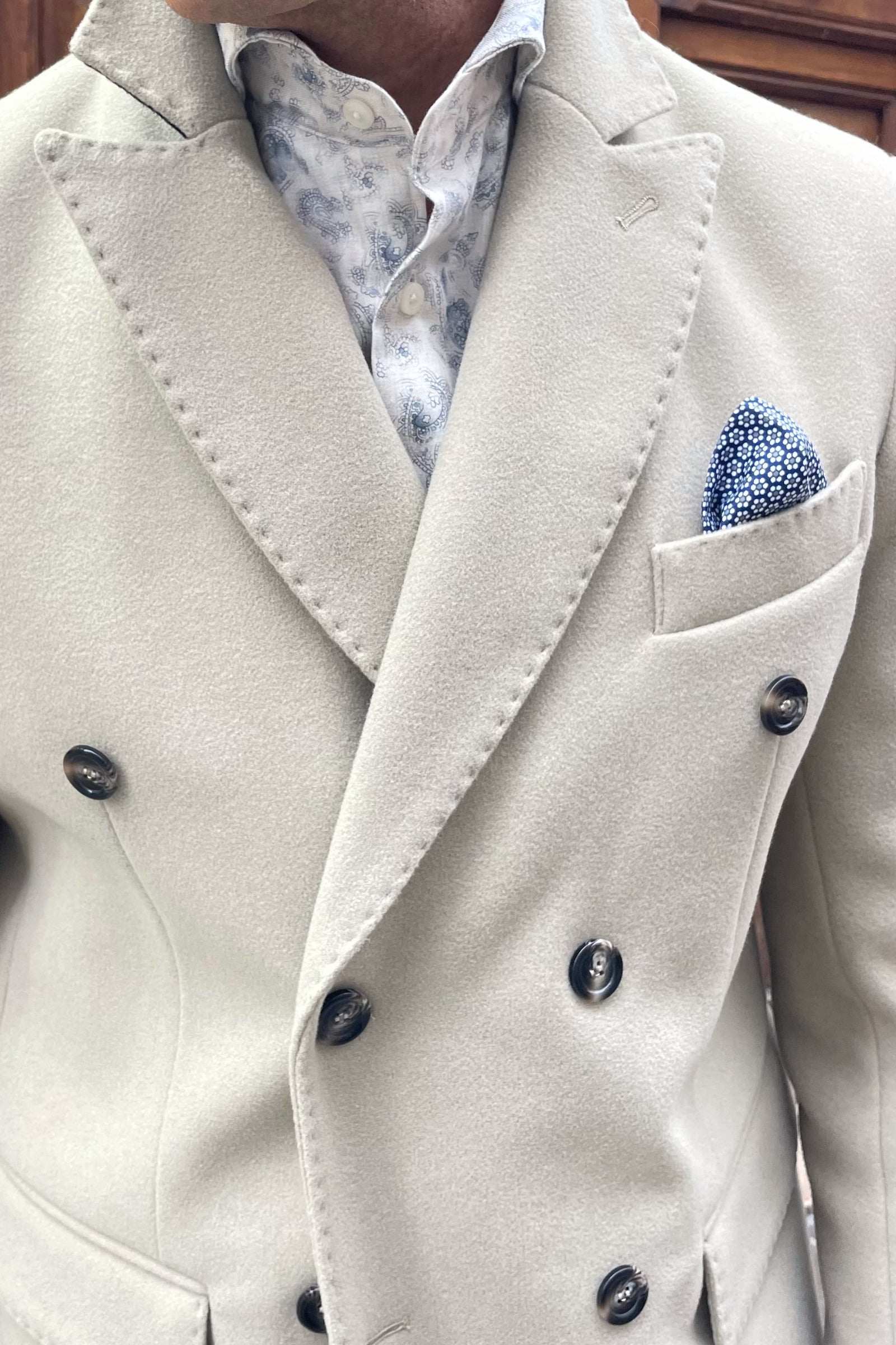 Detalle de solapa ancha y cuello estructurado de abrigo cruzado masculino italiano. UOMOMANIA