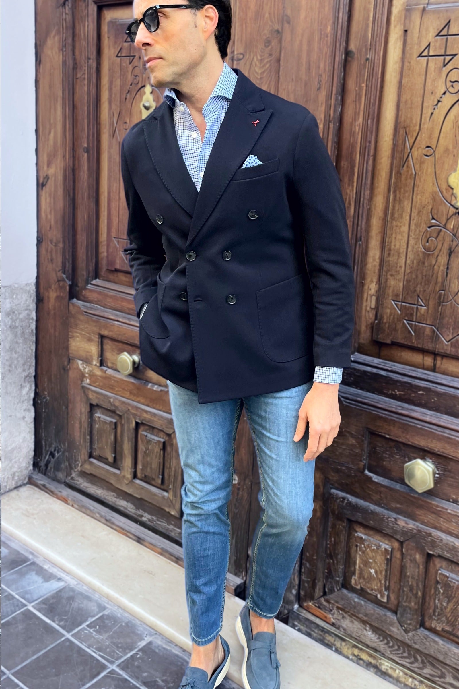 Outfit de hombre con americana cruzada azul marino combinada con vaqueros y camisa
